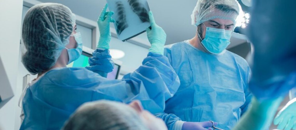 cirurgiao-proximo-ao-paciente-carrancudo-e-enfermeira-observando-a-radiografia-de-torax_376548-4518