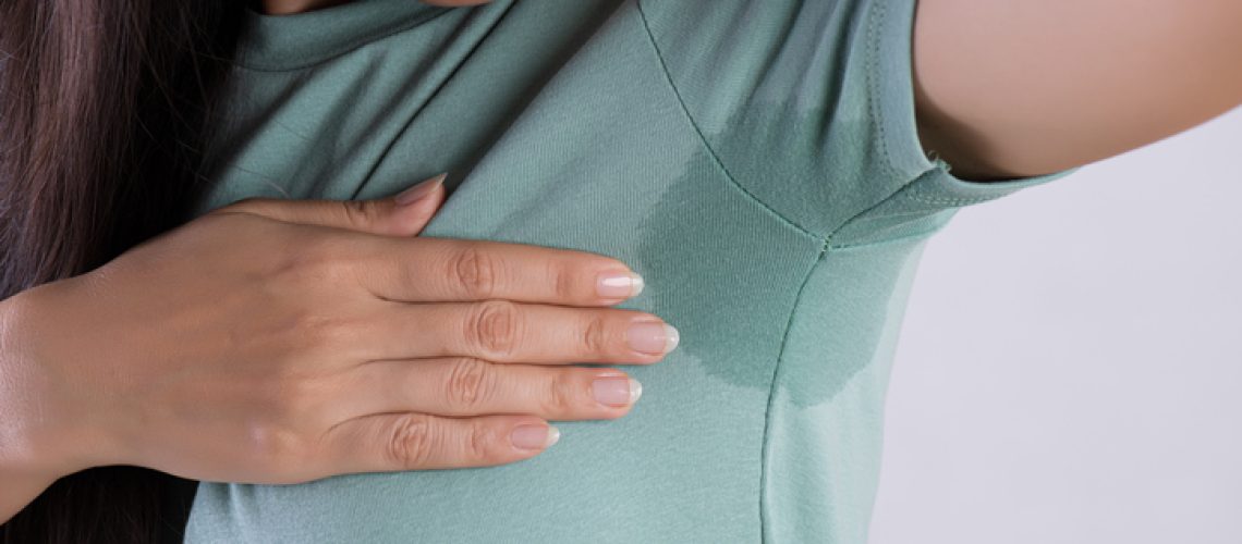 Close-up asian woman with hyperhidrosis sweating. Young asia woman with sweat stain on her clothes against grey background. Healthcare concept.